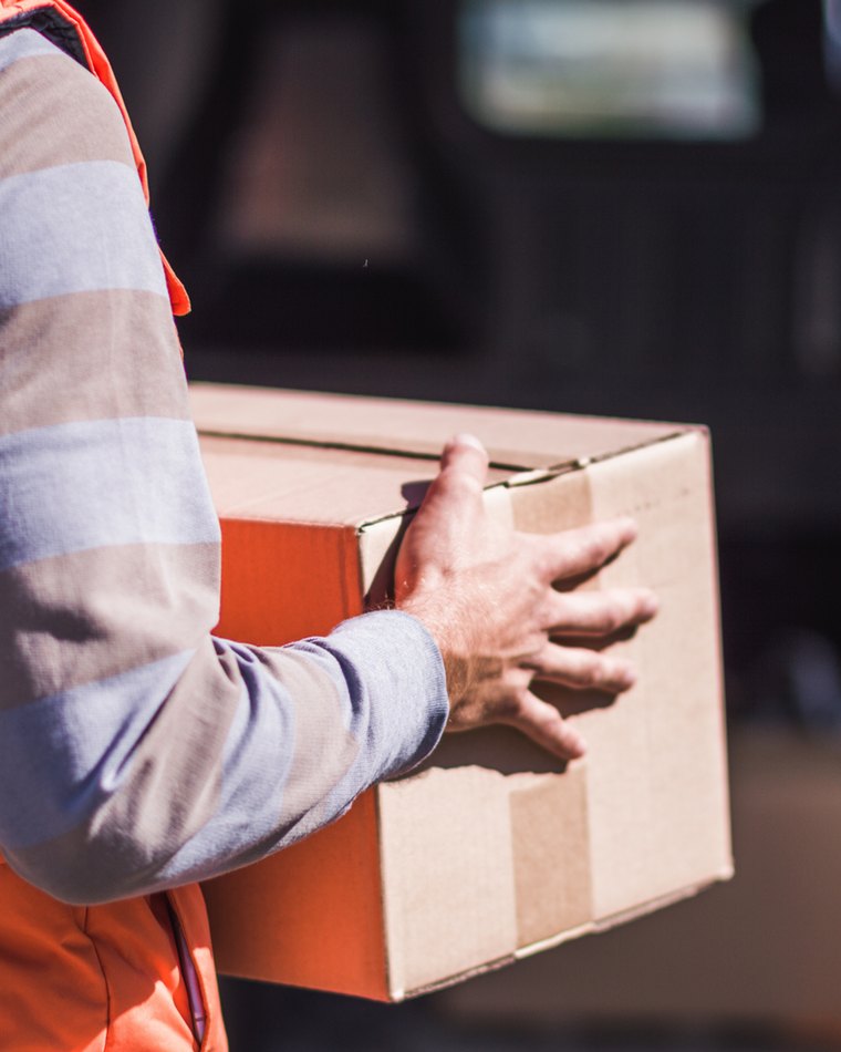 Mitarbeiter der HSG trägt ein Paket zur Verladung
